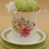 This is a frontal view showing the pincushion bobbin holder sitting on the trivet. The trim on the saucer is complemented by the fabric. This is a frontal view showing the pincushion bobbin holder sitting on the trivet. The trim on the saucer is complemented by the fabric.