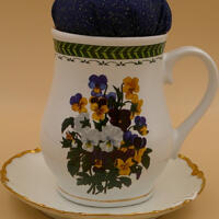 This is a front view of the pincushion attached to the saucer. It clearly shows the vibrancy of the bouquet of pansies. This is a front view of the pincushion attached to the saucer. It clearly shows the vibrancy of the bouquet of pansies.