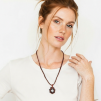 Orange Petal Bloom Necklace featuring handwoven burnt orange and black glass beads in a geometric floral pattern.