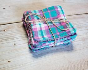 side view of a pink and teal plaid reusable facial square.