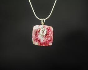 Square stone with a red and white mottled appearance. The stone has a silver wire swirl on the front, a silver bail and silver chain.