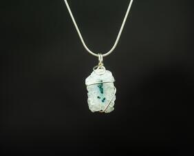 White stone pendant with a moss green inclusion and silver wire wrap on a silver chain.