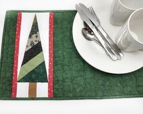 Set a beautiful Christmas table with these Christmas tree place mat.  Colorfully pieced tree and quilted with a holly back.

    What you get:   Set of 4 quilted and pieced Christmas tree place mats.
    Fabric color:  Cheerful green pieced tree with white and red gold dot side strip and dark green on each side of tree.  Holly on off white background on the back.
    Fabrics used:  Two layers of 100% cotton fabric, lined with one layer of cotton batting.  All have been preshrunk.
    Size:  12 inches x 18 inches.
    Care:  Hand or machine wash in cold water with like colors.  Air or tumble dry one warm.  No bleach. 
     Not for use with hot casserole dishes.
    Listing for 1 place mat only.  Dishes and silverware are not included.