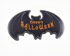 Black fabric with orange machine embroidered details and outlined in a dark gray.  It says Happy Halloween.