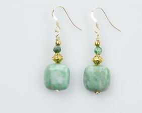 Light green gemstone earrings with gold decorative bead and a small green accent bead.
