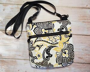 Top view of a yellow, gray and black medium crossbody with gunmetal zippers and a gunmetal Bass Creations logo.