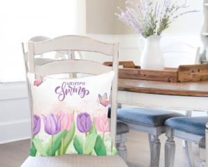 Welcome spring pillow cover displayed on a pillow on a dining chair