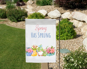 Spring has sprung gnome garden flag in a garden landscape