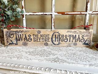 A handmade Christmas sign. Old time writing has been wood-burned onto a piece of reclaimed wood. Reindeer and holly are on either side. 