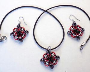 Matching earrings and pendant jewelry set in red and black, chainmaille pendant on a black leather cord necklace with hook wire earrings. Handmade by RainbowMaille in the USA
