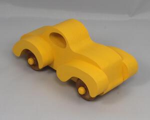 Handmade wooden toy car vintage style of a fat fendered coupe painted bright yellow with nonmarring amber shellac finished wheels. It is an excellent push toy for a younger child.