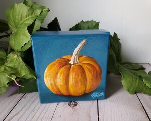 Small square painting of little orange pumpkin with teal blue background.