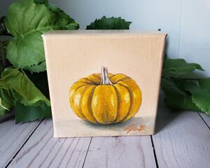 Photo of small square canvas painting of orange pumpkin with peach colored background