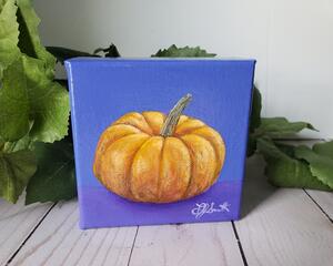 Photo of small square canvas painting of orange pumpkin with purple blue background
