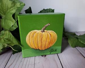 Photo of small square canvas painting of orange pumpkin with a olive green background