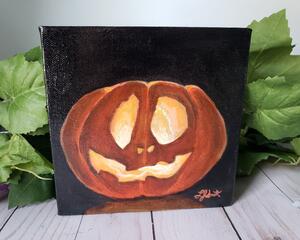 Photo of small square canvas painting of glowing jack o'lantern pumpkin with a black background