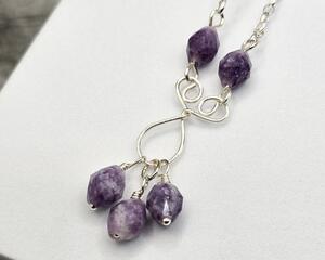 22 inch necklace featuring faceted sparkling purple lepidolite beads on a handcrafted wire pendant on stainless steel chain with a handcrafted hook clasp.