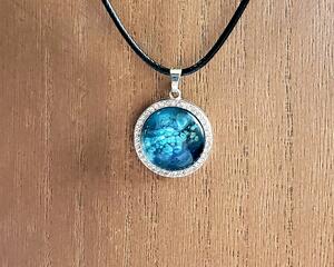 Various blues dark to light look bubble like. Set in Zinc Alloy base with rhinestone accents on the perimeter. Comes with your choice of chain or cord.