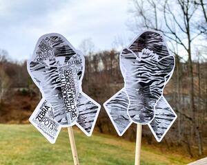 The word cloud and watercolor designs are shown on 2 sticks. Both ribbons are black and grey zebra stripes with a zebra head in the center. The word cloud design on the left is split in half with a word cloud on the left half of the ribbon and right half of the zebra. The right watercolor ribbon is all zebra patterened with a white border around the zebra for definition.