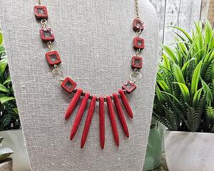 19 inch necklace featuring red graduated spike beads and red and gold square Czech glass beads, all on gold stainless steel chain.