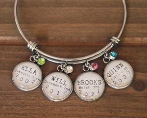 Silver wire bangle bracelet with 4 charms featuring names, birthdates, and birthstone charms.