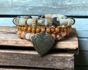 Wood bead bracelet on memory wire with heart charm on front and another charm on back.