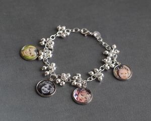 Silver bracelet with decorative balls featuring four personalized photo charms of children. 