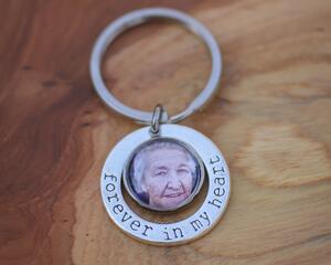 Silver photo key chain featuring older woman's photo encircled by Forever in My Heart accent charm on neutral wood background.