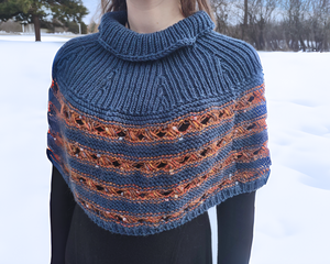 Women's Nursing Access Poncho with turtleneck that covers the shoulders and extends to the waistline. Features cobalt blue yarn on the top turtleneck part and has alternating stripes of cobalt blue and a metallic copper novelty yarn which has rust red and cobalt blue slubs in it, knit into a criscross stitch pattern. One Size Fits All.