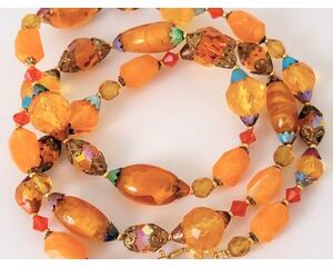 Long orange glass and Lucite beaded necklace with multicolor bead caps and a gold tone clasp.
