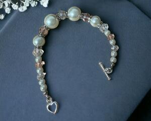 This is a beautiful handmade wedding bracelet. with white pearl beads and light pink faceted beads.  The clasp is a heart toggle.