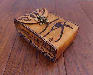 This is a Premium Handmade Leather Tarot Card Case featuring an ancient Egyptian motif, specially sized for slightly larger or deeper decks. The Eye of Horus, Thoth, a Winged Scarab and snippets of heiroglyphs from the Book of the Dead are all included. This tarot deck box has been specially hand dyed in antique amber tan and hand sewn with sapphire blue thread -- a gorgeous combination.

This special and unique find would make a beautiful gift for a tarot enthusiast in your life, or anybody looking to protect their tarot cards, oracle decks, or other small items. 

Featuring artwork permanently etched into the leather in black:

The front of this leather case displays the Eye of Horus.
Thoth is prominent on the back side along with the Winged Scarab that stretches over the top and onto the front flap.
Two sets of Egyptian Hieroglyphics cover the sides.