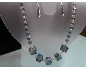 Denim glass jewelry set on a jewelry display. Statement necklace has focal point with larger square beads and tiny seed beads.