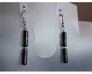 Black obsidian earrings hang on a jewelry stand. There are 2 tube smooth stones on each earring in this photo. 
