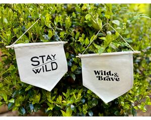 Two canvas pennant banners with different phrases that include Stay Wild and Wild & Brave.
