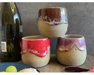 Three ceramic, hand-thrown wine tumblers, red, brown and purple. Each tumbler holds 12 ounces.