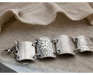 Sterling silver wide rectangular link bracelet with alternating complimentary patterns.