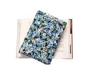 A padded book sleeve on top of an open book. The book sleeve is made with a blue floral Rifle Paper Co. cotton print.