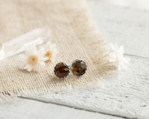 Smokey Quartz and sterling silver earrings on linen fabric with dried flowers and white wood background. 
