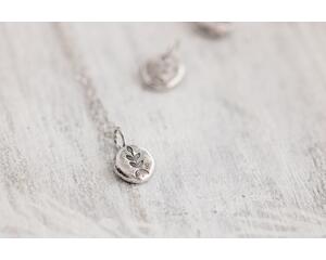 small silver charm made from a recycled silver ball hammered flat and stamped with a fern design on a sterling silver chain.
