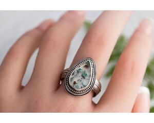 Pear shaped clear agate stone with flecks of greens blues copper in a sterling silver bezel surrounded by beaded wire on floral comfort band