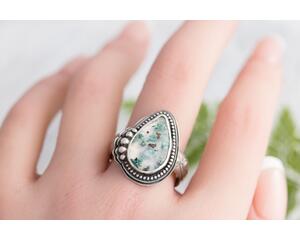 Sterling ring with pear shaped clear agate stone with flecks of greens blues and copper in a sterling silver bezel surrounded by beaded wire