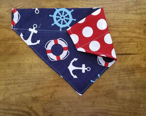 Over the collar dog bandana that is reversible from anchors to red with white polka dots.