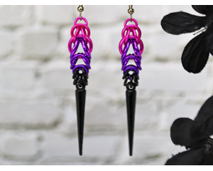 Chainmaille earrings in pink, violet and black. Earrings taper outward slightly before narrowing, and a long black spike hangs at the bottom
