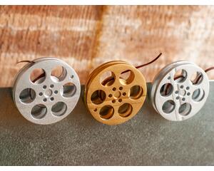 front view of a gold and silver miniature movie reel magnets hanging on fridge
