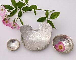 Set of three nesting trinket dishes made from a vintage silverplated brass serving tray. Largest dish is a bird shape, two smaller dishes are round. Photo shows all three side by side, one with tiny rose blossom floating in water.