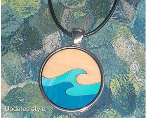 Round wooden necklace in stainless steel cabochon with black leather necklace. Birch wood has a natural on top with aqua and blue waves.