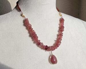 Necklace with pink quartz pendant with pink quartz nuggets, cream colored shell beads, and tiny red garnet beads with gold hook clasp