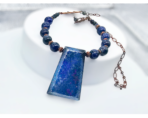 Necklace with blue lapis lazuli trapezoidal prism pendant, copper spacer beads, and round lapis lazuli beads on copper chain with hook clasp