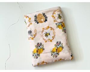 this beehive book sleeve has a light pink background with beehives and bees all over the bee book cover. The bee book holder has a pocket